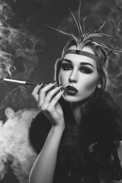 Beautiful girl with smoky eyes and red lips holding cigarette - Photo, Image