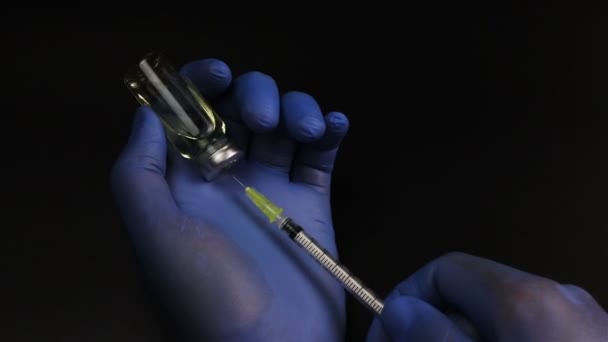 Ruiskun neula lävistää lasisen injektiopullon kumitulpan ja täyttää lasisen ampullin mustalla pohjalla
 - Materiaali, video