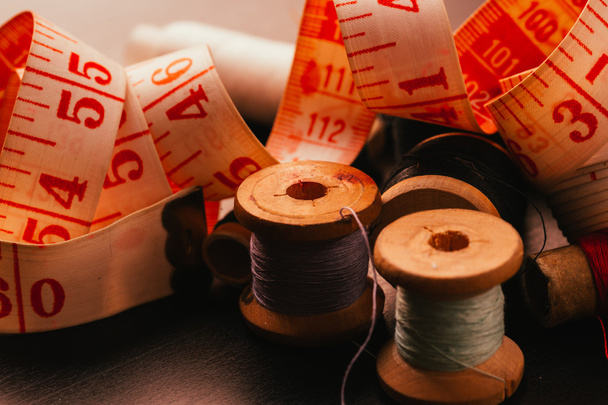 lot Vintage spools of thread thimble and measuring tape on a wooden background - Foto, afbeelding