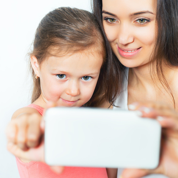 Cute child and mother make selfie on mobile phone - Foto, imagen