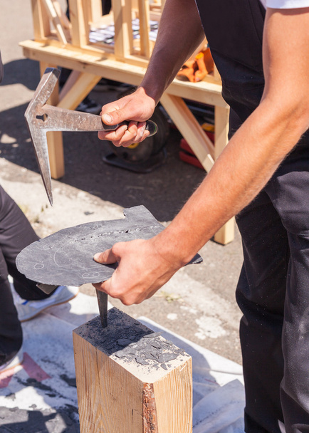 Trabajador produce pizarra para techos usando un martillo de pizarra
 - Foto, Imagen