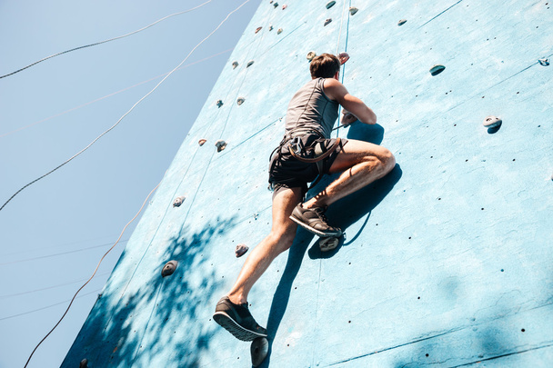 Young man doing exercise in mountain climbing on practice wall - Fotoğraf, Görsel