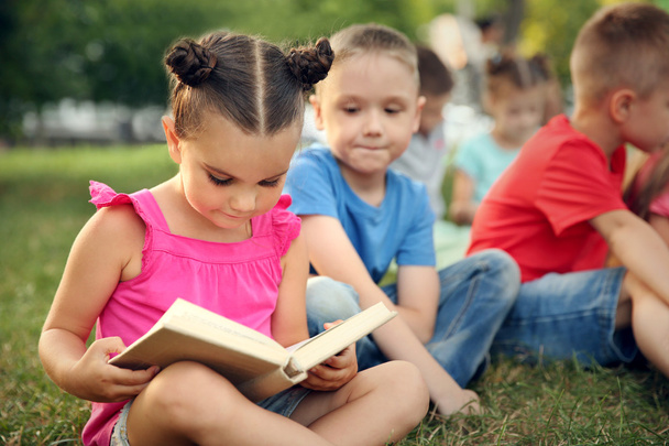 Group of happy kids reading books in park - Foto, imagen