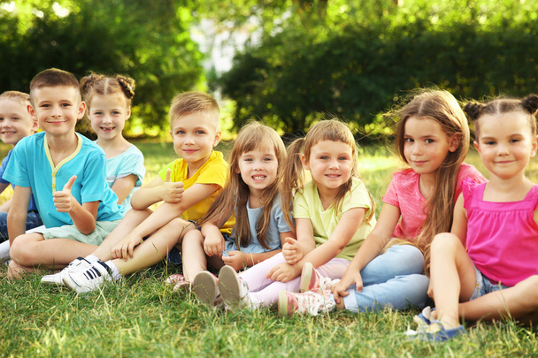 Boldog gyerekek ül a fűben park - Fotó, kép