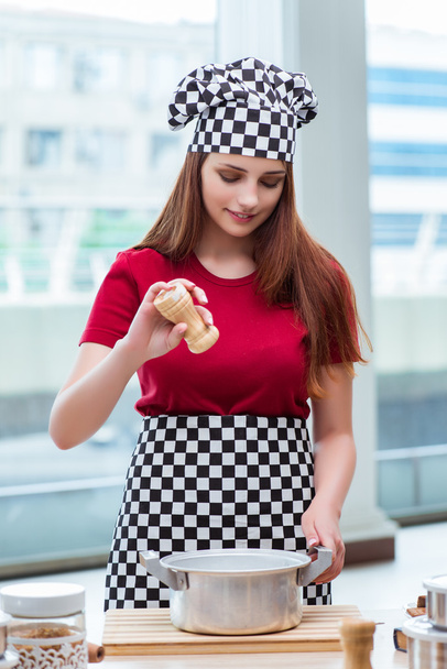 junge Hausfrau bereitet in Küche Suppe zu - Foto, Bild