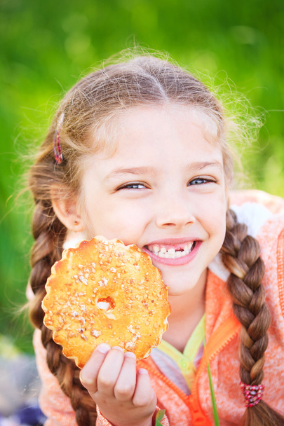 süßes Mädchen mit einem gefallenen Toth, das Kekse in der Hand hält - Foto, Bild
