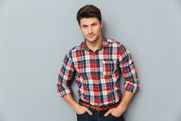 Handsome young man standing with hands in pockets - Foto, imagen