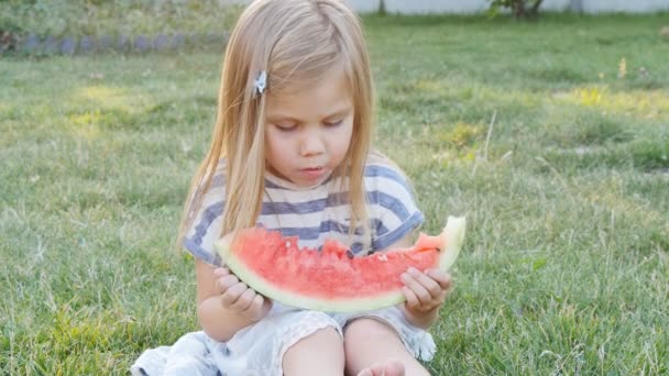 Petite fille mignonne mangeant pastèque sur l'herbe en été
 - Séquence, vidéo