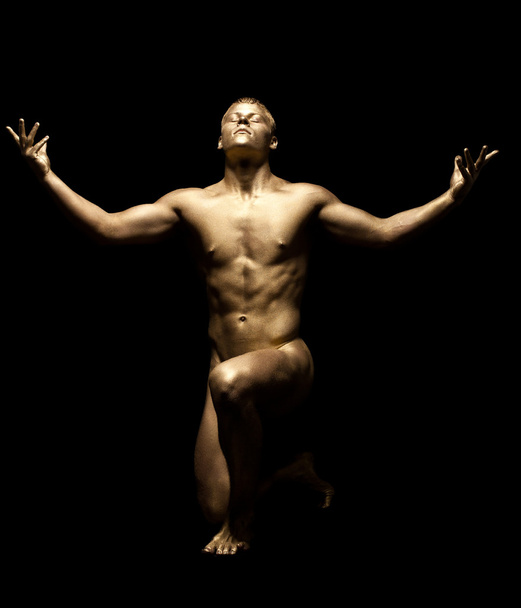 Strong man posing nude in dark with gold skin - Photo, Image