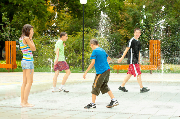 Teini-ikäiset pojat ja tytöt hauskaa kaupungeissa vesi suihkulähde kuumana kesäpäivänä
 - Valokuva, kuva