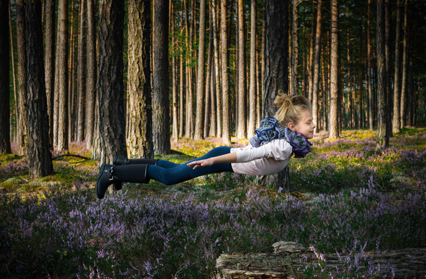 Beautiful blond girl levitates in the forest. - Photo, Image