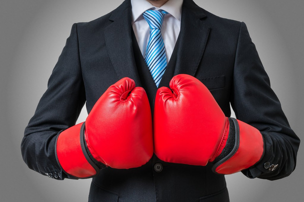 Boxing businessman with red gloves on gray background. - Zdjęcie, obraz