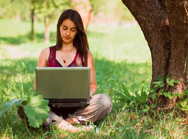 Happy young woman using her laptop outdoors. - Fotoğraf, Görsel