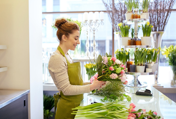smiling florist woman making bunch at flower shop - Фото, изображение