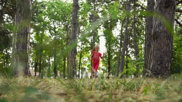 Girl running in the park among the trees. Defocused shooting. - Πλάνα, βίντεο