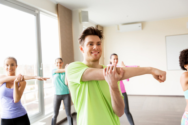 group of smiling people stretching in gym - Фото, изображение