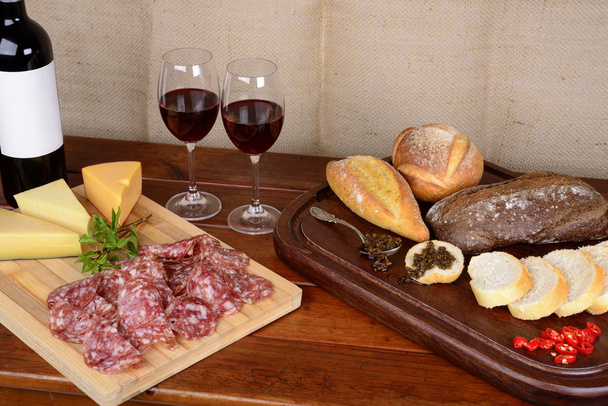 Колбасные изделия и сырное ассорти, хлеб, чимичурри и красное вино - Фото, изображение