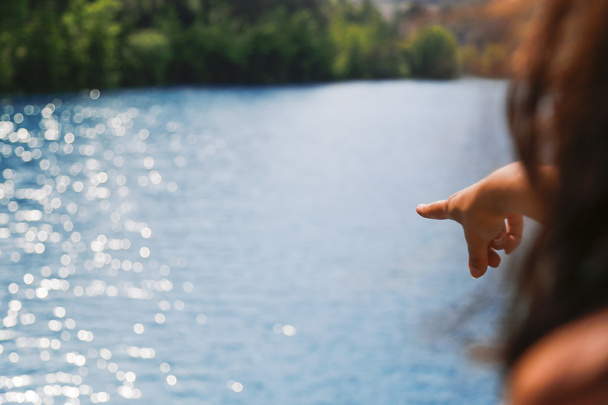 Woman hand point at blue lake - Fotoğraf, Görsel
