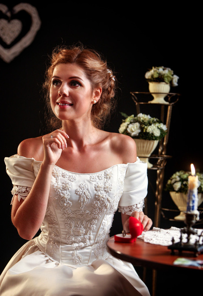 счастливая девушка в свадебном платье сидит за столом
. - Фото, изображение