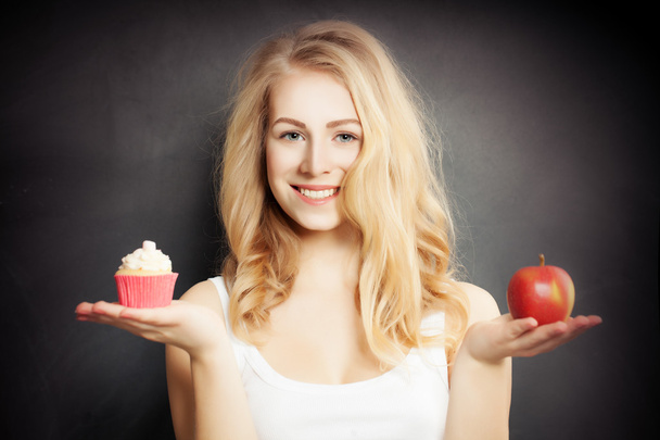 Dieta. Donna sana che tiene mela rossa e torta
 - Foto, immagini