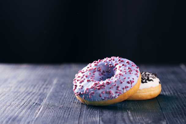 Donuts mit blauem und Vanille-Sahnehäubchen auf dunklem Hintergrund - Foto, Bild