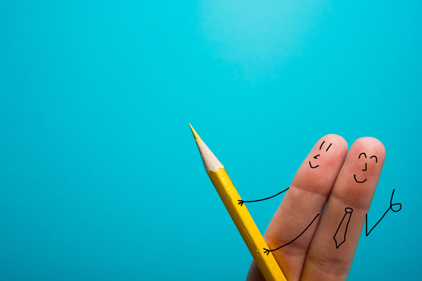 Смешные пальцы, рисующие жёлтый карандаш на синем фоне. Концептуальная мотивационная картина
 - Фото, изображение