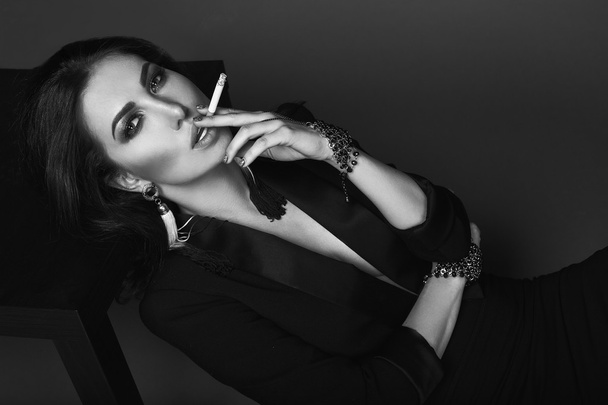 Elegant hot brunette woman smoking a cigarette - 写真・画像