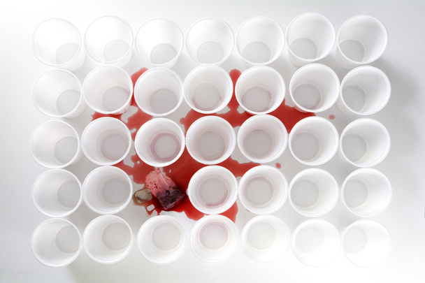 bleeding teabag with red tea between rows of white plastic cups, mobbig victim - Foto, afbeelding