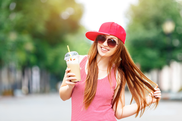 Fashion city portrait of stylish hipster woman with milk shake, red striped dress, red cap and sneakers, makeup, long brunette hairs, walking alone at weekend, enjoy vacation in Europe, modern trendy - Fotoğraf, Görsel