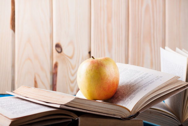 Stapel boeken en apple op een blauwe houten plank - Foto, afbeelding