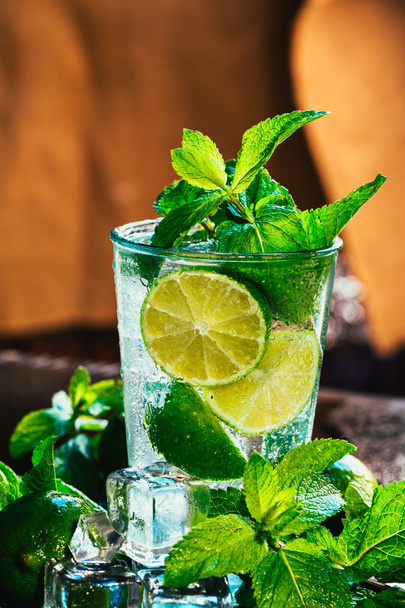 glass of mojito with lime and mint ice cube close-up red straw on orange background - Фото, изображение