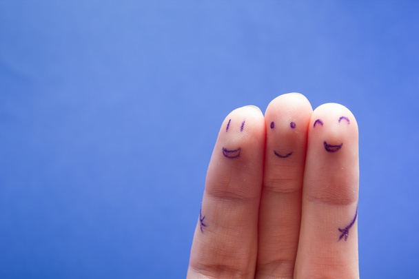Kolme hymyilevää sormea, jotka ovat iloisia ystävyydestään. Ystävyys tiimityöskentely konsepti sinisellä pohjalla kopioi tilaa mainoksen tekstiä
. - Valokuva, kuva