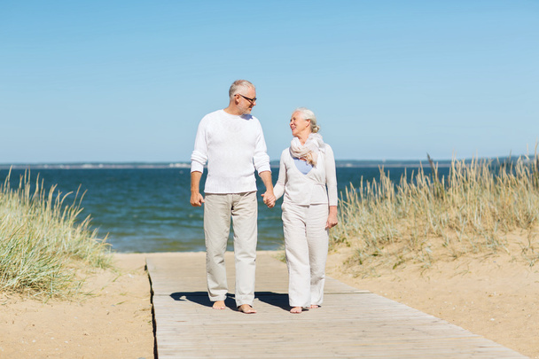 happy senior couple holding hands on summer beach - Fotoğraf, Görsel