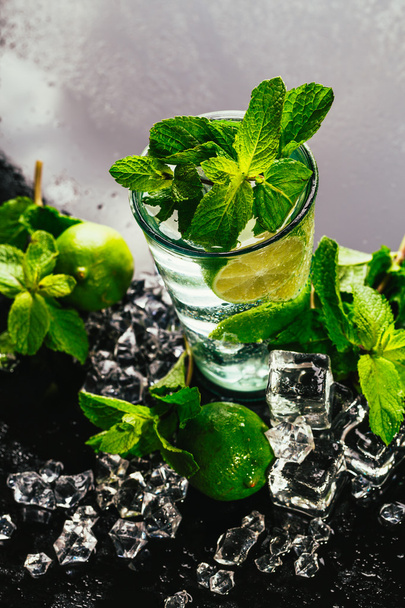 glass of mojito with lime and mint ice cube close-up red straw on dark background - Фото, изображение