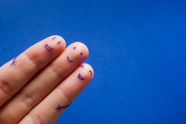 Три усміхнені пальці, які дуже раді друзям. Концепція командної роботи дружби на синьому фоні з копіювальним простором для тексту реклами
. - Фото, зображення