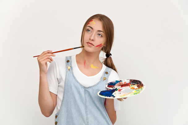 mooie jonge kunstenaar holding een palet en penselen.  - Foto, afbeelding