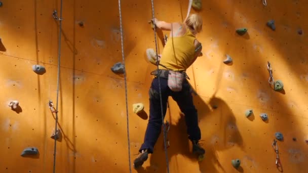 Climbing wall in the open air. Girl on the orange wall - Footage, Video