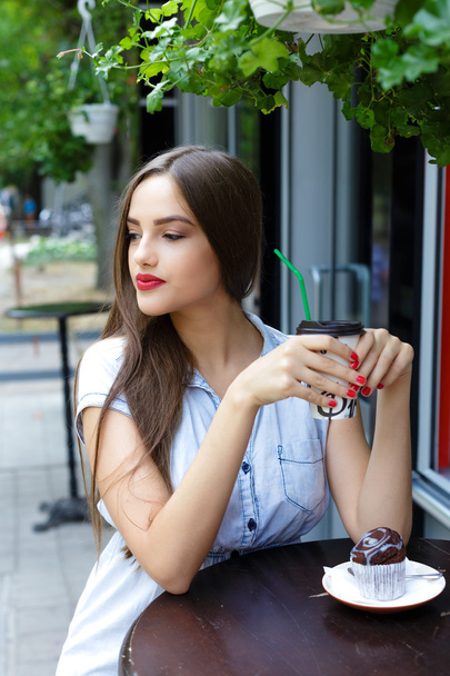 Задумчивая красивая девушка в кафе на открытом воздухе пьет кофе с
  - Фото, изображение