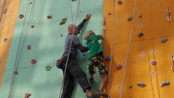 Climbing wall in the open air. Young man and little boy on the wall - Footage, Video