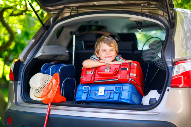 Little kid boy sitting in car trunk just before leaving for vaca - Foto, Imagem