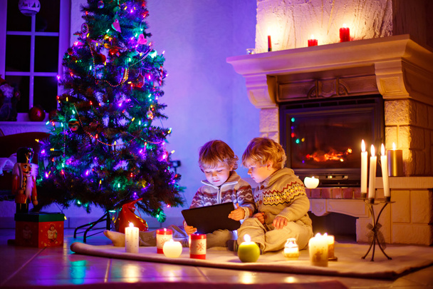 Deux petits enfants assis près d'une cheminée à la maison à Noël
 - Photo, image