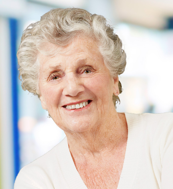 Portret van senior vrouw die lacht tegen een abstracte achtergrond - Foto, afbeelding