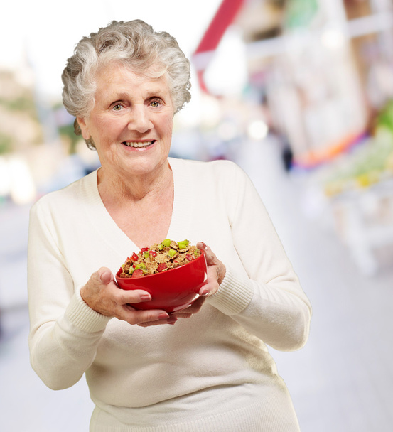 retrato de mulher idosa saudável segurando tigela de cereais na rua
 - Foto, Imagem