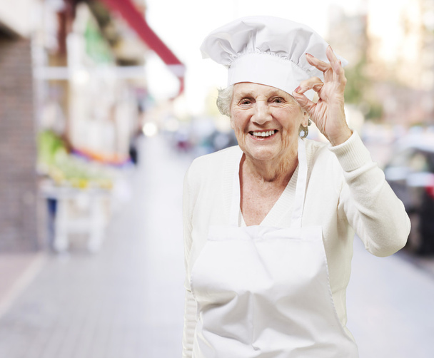starší žena vařit, dělá vynikající symbolem proti pouliční bac - Fotografie, Obrázek