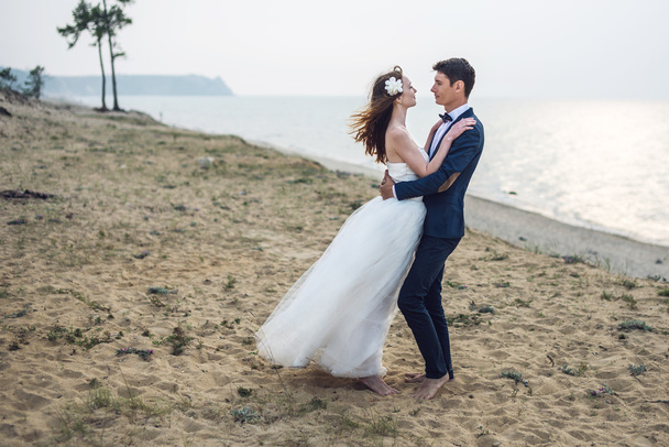 feliz pareja joven recién casada celebrando en la hermosa playa
 - Foto, Imagen