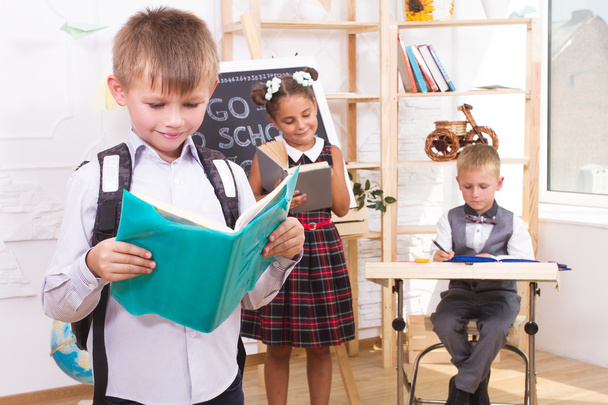 Portré egy fiú olvas egy könyvet a háttérben az osztálytársaikkal.  - Fotó, kép