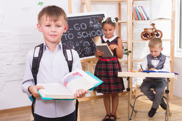 Portrait of a boy reading a book on the background of their classmates - Φωτογραφία, εικόνα