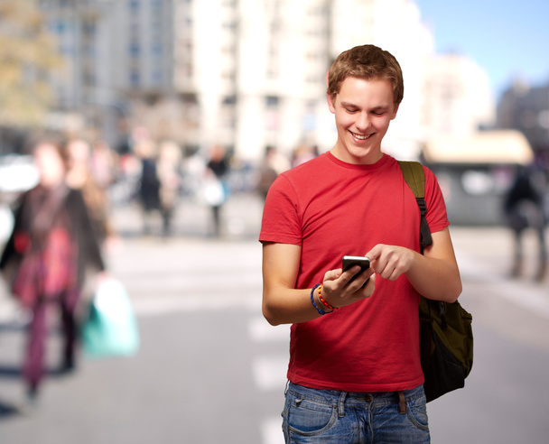 ritratto di un giovane che tocca lo schermo mobile in una strada affollata
 - Foto, immagini