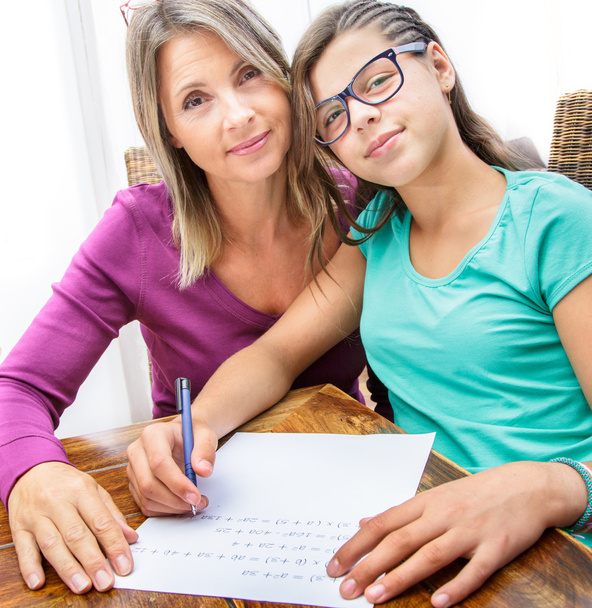 pretty teen girl doing its homework in complicity with her mother - Photo, Image