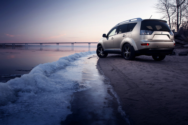 Car Mitsubishi Outlander stay on ice coast at winter sunset - Foto, Imagem